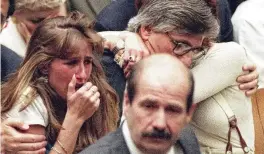  ?? AP ?? Fred Goldman, father of Ron Goldman, hugs his wife, Patti, as his daughter, Kim (left), reacts during the reading of the not-guilty verdicts in O.J. Simpson’s double-murder trial in 1995, in Los Angeles. Simpson was acquitted in the murders of Goldman and Simpson’s ex-wife Nicole. Foreground is Los Angeles Police Detective Tom Lange.
