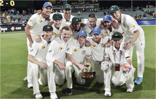  ??  ?? ADELAIDE: Australia’s team members pose with the winning trophy after defeating New Zealand in the first day-night cricket Test match at the Adelaide Oval yesterday. — AFP