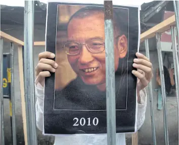  ?? AP ?? An exiled Tibetan holds a portrait of Chinese Nobel laureate Liu Xiaobo behind bars during a street protest in India yesterday.