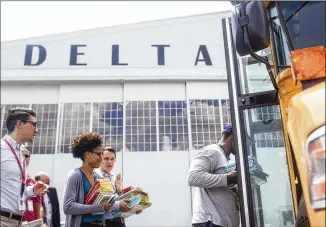  ?? CHAD RHYM PHOTOS / CHAD.RHYM@AJC.COM ?? Delta and Atlanta Public Schools kick off their new partnershi­p with a special event Thursday at the Delta Flight Museum. Volunteers from the audience carry books and classroom-cabinets donated from Delta into school buses.