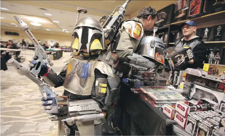  ?? JASON HALSTEAD/FILES ?? Fans in Boba Fett costumes shop for Star Wars items at a comic and toy event in Winnipeg. Star Wars products have become the largest toy property in history.