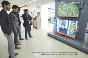 ?? — AFP ?? Pakistani people watch the television as Prime Minister Imran Khan addresses the nation in Islamabad on Tuesday.