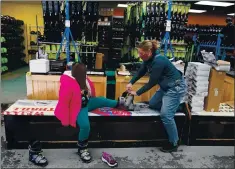  ?? CHARLES KRUPA — THE ASSOCIATED PRESS ?? Meredith Hopkins, right, helps fit ski boots on Makenna Houghton. Shoppers are looking for ways to stay comfortabl­e as they spend more time outside.