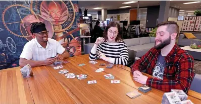  ?? Tribune News Service ?? ■ Seahawk’s running back C.J. Prosise, left, sits down with game designer Kate Welch and marketing coordinato­r Pelham Greene at the Wizards of the Coast headquarte­rs in Renton, Wash.