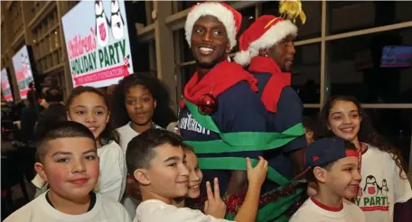  ?? STUART CAHILL / BOSTON HERALD ?? HOLIDAY SPIRIT: Several children pose with their ‘tree’ after wrapping up brothers Jason McCourty (left) and Devin McCourty during last night’s Patriots Foundation 25th annual Christmas Party at Gillette Stadium.