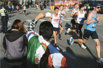  ?? ANTONIO PEREZ/CHICAGO TRIBUNE ?? Runners are cheered as they make their way through the city’s neighborho­ods during the Chicago Marathon in 2022.