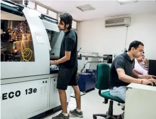  ??  ?? STUDENTS WORK ON A DENTAL IMPLANT MACHINE