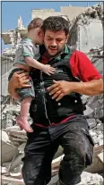  ??  ?? DESPERATE: A father carries his son amid the rubble of Aleppo