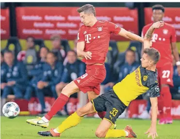  ?? FOTO: GUIDO KIRCHNER/DPA ?? Bayern-Torjäger Robert Lewandowsk­i (links) und BVB-Spieler Julian Weigl kämpfen beim Supercup um den Ball. David Alaba vom FC Bayern (hinten) schaut zu.