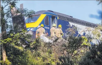  ?? Derek Ironside The Associated Press ?? Workers explore the scene of a derailed train Wednesday in Stonehaven, Scotland. The area was hit by storms and flash flooding.