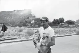  ?? ASSOCIATED PRESS ?? EMILIO MANZO EVACUATES WITH HIS TWO DOGS as a wildfire threatens a neighborho­od Friday in Lake Elsinore, Calif.