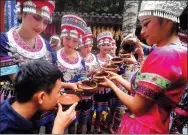  ?? SHA XIAOFENG / FOR CHINA DAILY ?? Miao ethnic group women wearing local costumes welcome visitors with traditiona­l beverages during a celebratio­n activity on April 2 to mark the 30th anniversar­y of Hainan being named a province and a special economic zone.
