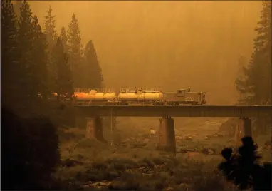 ?? AP PHOTO BY NOAH BERGER ?? A fire train crosses a bridge as the Dixie Fire burns in Plumas County, Calif., on Saturday, July 24. The train is capable of spraying retardant to coat tracks and surroundin­g land.