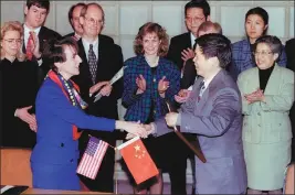  ?? PROVIDED TO CHINA DAILY ?? Above: Barshefsky and Deputy Foreign Trade Minister Sun Zhenyu (right) shake hands after signing an agreement on Feb 26, 1995, in Beijing to strengthen safeguards against intellectu­al property piracy in China and widen market access for US companies.