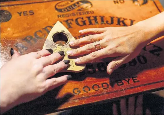  ?? PATRICK CONNOLLY/ORLANDO SENTINEL ?? Raven Star, a psychic witch, helps visitors from the Palm Beach area with a Ouija board session in Cassadaga.