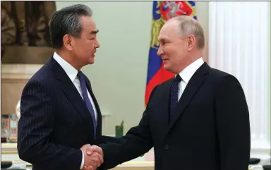  ?? (AP/Sputnik/Anton Novoderezh­kin) ?? Russian President Vladimir Putin greets Chinese Communist Party foreign policy chief Wang Yi at the Kremlin on Wednesday. Putin said the two countries’ cooperatio­n on the world stage “is particular­ly important for stabilizin­g the internatio­nal situation.”