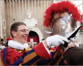  ?? PLINIO LEPRI — THE ASSOCIATED PRESS ?? FILE — In this file photo, an unidentifi­ed Swiss Guard puts his helmet on the head of his girlfriend during a ceremony in the “Honour Courtyard” at the Vatican. The world’s oldest standing army is getting some new headgear. The Swiss Guards plan to...