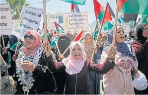  ?? AFP ?? Palestinia­n women chant and lift placards and national flags during a demonstrat­ion against Israel’s West Bank annexation plans in Gaza City on Wednesday.