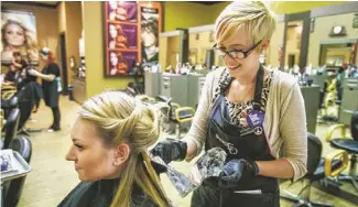  ?? CHARLIE LEIGHT/THE REPUBLIC ?? Jessie Donoho checks Emma Doty’s color at the Madison Avenue Salon & Day Spa in Chandler. Doty's peek-a-boos are violet-to-pink ombre, which fade from violet to pink.