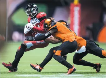  ?? CP PHOTO ?? Bakari Grant of the Calgary Stampeders is brought down by T.J. Lee and Garry Peters of the B.C. Lions during a Saturday game in Vancouver.