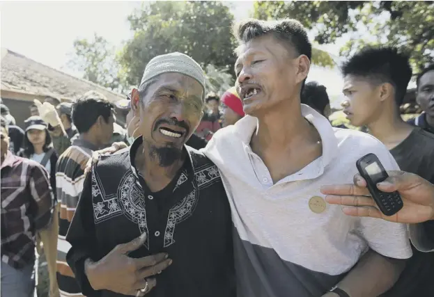  ??  ?? 0 Relatives wait for news as rescue teams recover the bodies of victims killed in the earthquake on the Indonesian island of Lombok