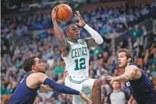  ?? AP ?? Boston Celtics’ Terry Rozier shoots between Minnesota Timberwolv­es’ Tyus Jones (left) and Nemanja Bjelica during the second quarter of their NBA clash in Boston.