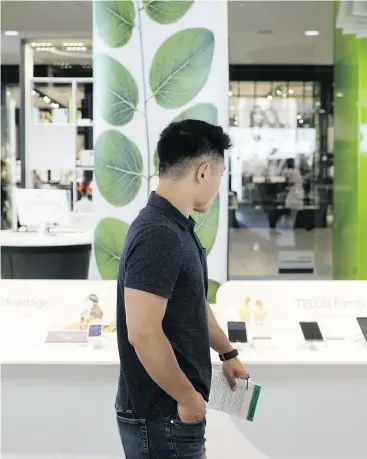  ?? BRENT LEWIN / BLOOMBERG FILES ?? A customer browses smartphone­s at a Telus store. The company added 87,000 wireless customers in its second quarter, but average billings per user was up just 0.6 per cent.