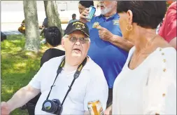  ??  ?? Ron Organek, Greater Middletown Military Museum founder, speaks to one of the dozens of people who gathered on Friday to watch the spectacle. The copter is now on display at the museum, which is expected to open in the next couple months.