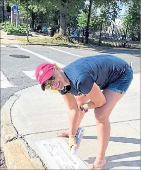  ?? CHERYL A. CUDDAHY / SENTINEL & ENTERPRISE ?? Christine Pelletier, president of the Leominster Rotary Club, stencils a storm drain Thursday in downtown Leominster, warning residents not to dump contaminan­ts that would flow into nearby rivers.