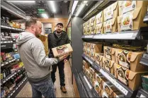  ?? STEPHEN BRASHEAR / GETTY IMAGES ?? Shoppers Peter Ray (left) and Peter Freese examine pre-made meals Monday at the Amazon Go convenienc­e store in Seattle, which is now open to the public.