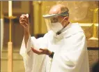  ?? Christian Abraham / Hearst Connecticu­t Media ?? Father Peter Adamski wears PPE while presiding over Holy Communion at the first indoor weekend Mass since the beginning of the coronaviru­s pandemic at St. James Roman Catholic Church in Stratford on Saturday.