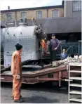  ?? MIKE CURTIS ?? Members of the restoratio­n team, Jeremy Mead and John Hall, look on as Derek Binner lights the fire for the initial steam test on the boiler of ‘Ironclad’ No. 957 on July 24.