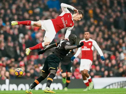  ?? — Reuters ?? Over the top: Arsenal’s Laurent Koscielny colliding with Hull’s Oumar Niasse in the English Premier League match at the Emirates yesterday.