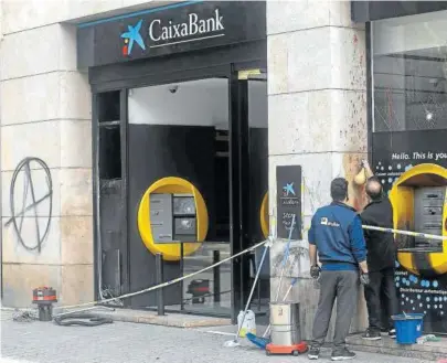  ?? Foto: Efe ?? Operarios reparan una entidad bancaria atacada en los disturbios del sábado.
