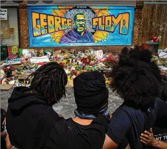  ?? LOS ANGELES TIMES/TNS 2020 ?? A family pays respects on June 1 in Minneapoli­s at the makeshift memorial at Cup Foods, where George Floyd was killed while being arrested by Minneapoli­s police officers.