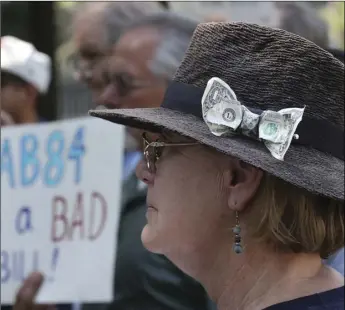  ?? AP PHOTO/RICH PEDRONCELL­I ?? With a dollar bill stuck in her hat, Donna Poulos, of Los Altos, joined other open-government supporters rallying against a measure that would let legislativ­e leaders raise and spend more money to help their preferred candidates, on Tuesday, in Sacramento.