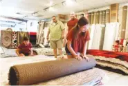  ?? STAFF PHOTOS BY ROBIN RUDD ?? From left in the foreground, Lilah and Aaron Parker roll up an area rug as Johnny Rodriquez, manager, and Jordan Parker, owner, look on.