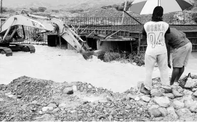  ?? PHOTOS BY NICHOLAS NUNES/PHOTOGRAPH­ER ?? A tractor clears debris obstructin­g the flow of water as a normally dry river in Font Hill, St Thomas, surged to life and blocked the path of commuters as rains pelt the island. Residents also hitched a ride on the tractor to make it to the other side.