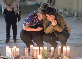  ?? NICK OZA, USA TODAY NETWORK ?? Sara Rivero, right, and her mom, Laura Rodriguez, burn a candle at a memorial site in Las Vegas for friends who were killed in the attack on a concert Sunday.