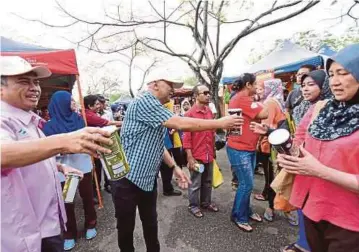  ??  ?? ABDUL Ghariff (tengah) memberi barangan percuma kepada pengunjung sempena Majlis Pelancaran Pra-Syawal anjuran FAMA di Pasar Tani Pekarangan Stadium Shah Alam.