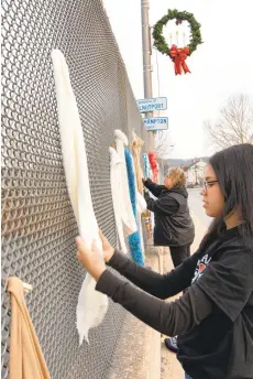  ??  ?? Kaylyn Lugo hangs scarves Friday afternoon on the overpass above the Lehigh River in Slatington for Project Warm and Cozy, which helps those in need.