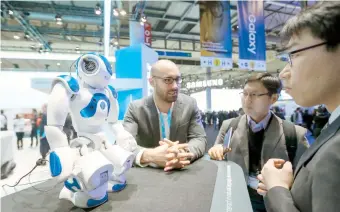  ??  ?? Visitantes al MWC de Barcelona observan un robot con tecnología IBM.