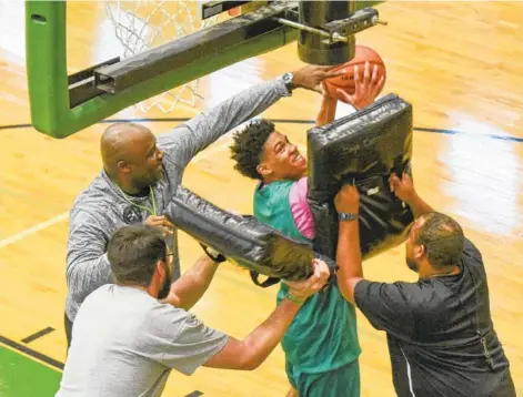  ?? STAFF PHOTO BY TIM BARBER ?? East Hamilton head coach Rodney English, top left, and assistants Zach Roddenberr­y and Kendall Toney, right, push in on Cam Montgomery in a box-out drill during Monday's practice for today's state tournament opener.