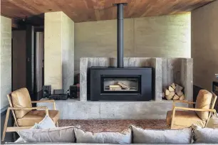  ??  ?? The owners wanted a relaxed family home of rammed earth constructi­on. The television is tucked behind the fireplace, at one end of the snug.