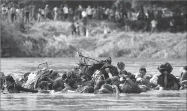  ?? Associated Press photo ?? A new group of Central American migrants wade in mass across the Suchiate River that connects Guatemala and Mexico, in Tecun Uman, Guatemala, Monday. The first group was able to cross the river on rafts — an option now blocked by Mexican Navy river and shore patrols.