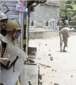  ?? —AFP ?? KASHMIR: Kashmiri protestors (right) throw stones towards Indian government forces during clashes in Srinagar yesterday.