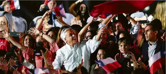  ?? Martin Bernetti - 16.nov.2017/AFP ?? O então candidato direitista Sebastián Piñera (centro) sacode a bandeira do Chile em seu último comício das eleições presidenci­ais, em Santiago