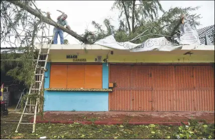  ?? AP PHOTO ?? An employee works to remove a felled tree from a rooftop in the aftermath of Hurricane Irma, in Fajardo, Puerto Rico, yesterday.