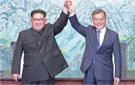  ??  ?? North Korean leader Kim Jong Un and South Korean President Moon Jae-in raise their hands after signing a joint state ment Friday at the border village of Panmunjom in the Korean Peninsula’s Demilitari­zed Zone.