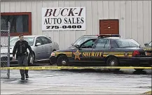  ?? MARSHALL GORBY / STAFF ?? A Montgomery County Sheriff’s Office deputy surveys the scene of Monday’s shooting at Buck-I Auto Sales at 2801 N. Dixie Drive. Two men ages 79 and 59 were discovered inside the business shot to death after deputies were dispatched.